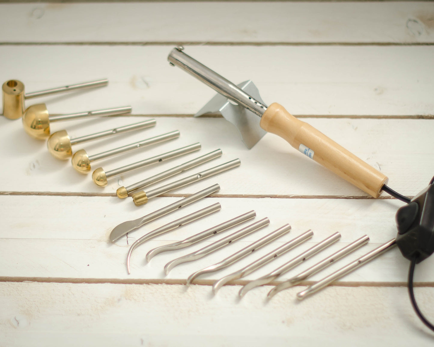 Set of metal fabric flower making tools with a wooden handle on a light wooden surface