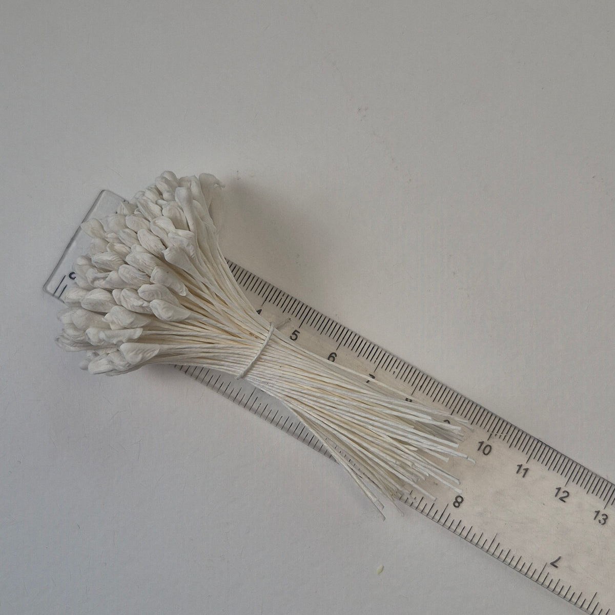 A bundle of 144 single-sided extra-large size XL white decorative Japanese flower stamens for lilies and tulips on matching white threads, featuring large handmade elongated heads measured against a ruler