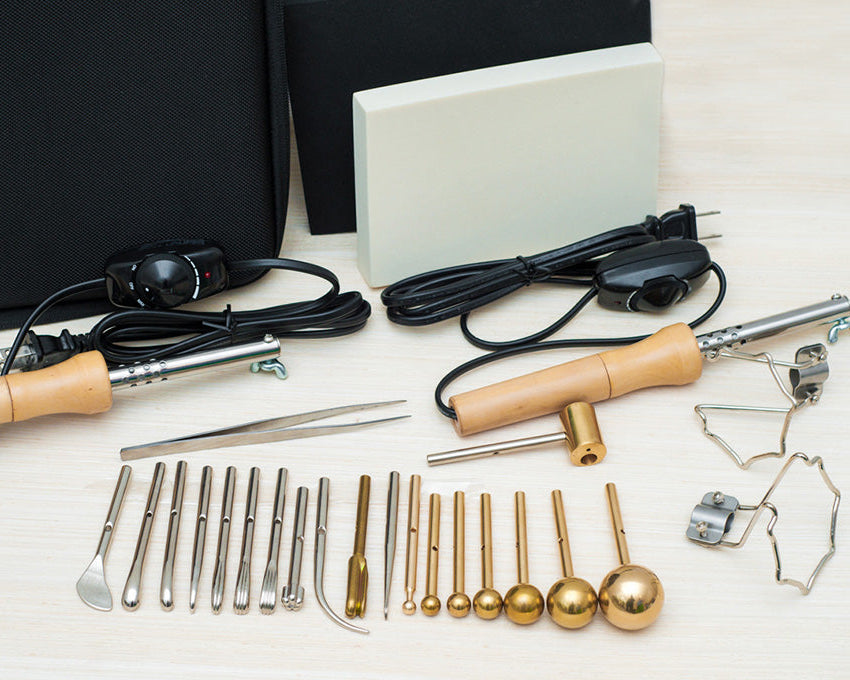 Collection of metal tools and accessories for fabric flowers making on a white surface with a black background.