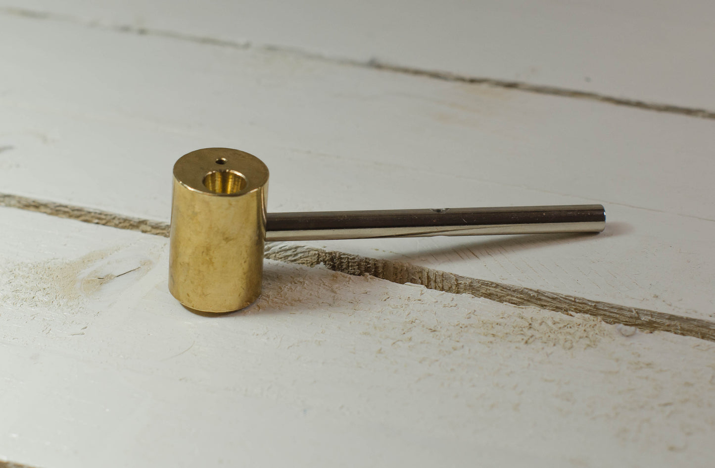 Gold-colored tool Stem Iron Tip on a light wooden surface