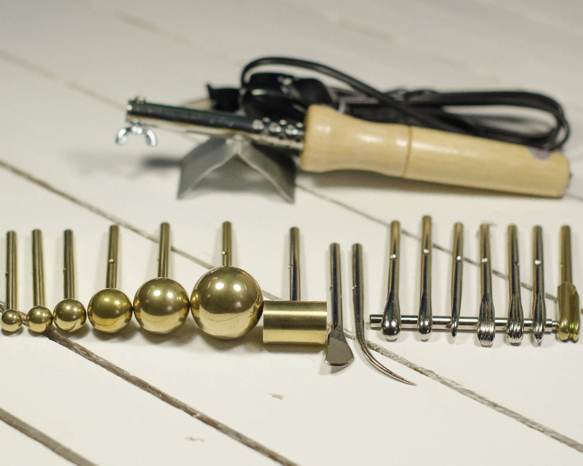 Set of gold metal flower shaping tools on a white wooden surface