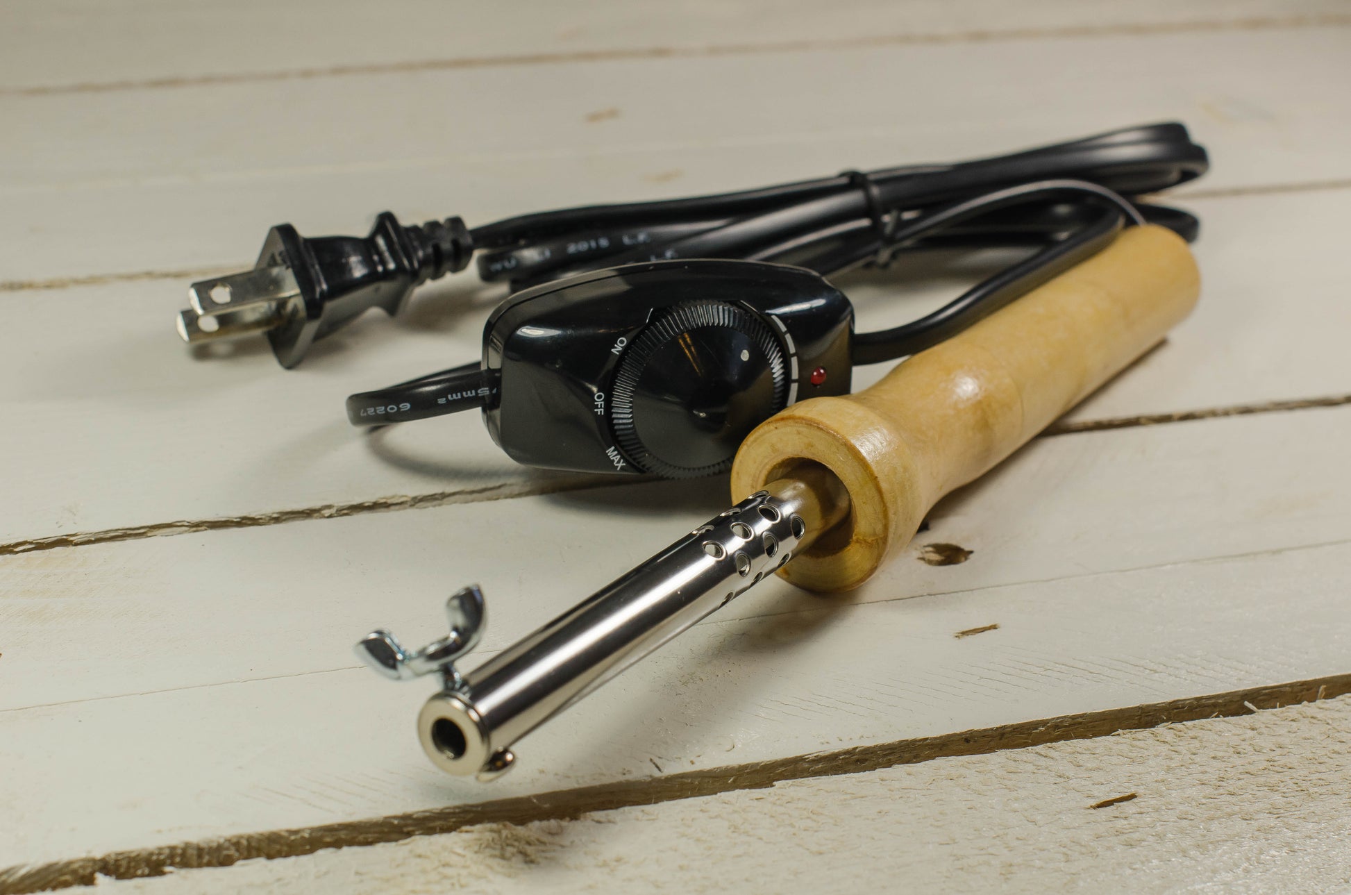 Soldering iron with wooden handle and power cord on a light wooden surface