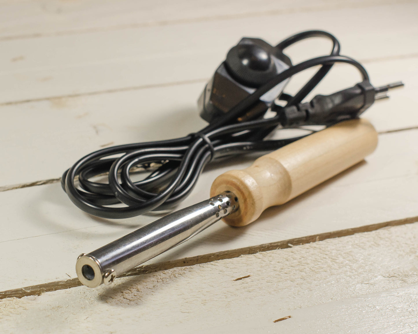 Soldering iron with wooden handle on a light wooden surface