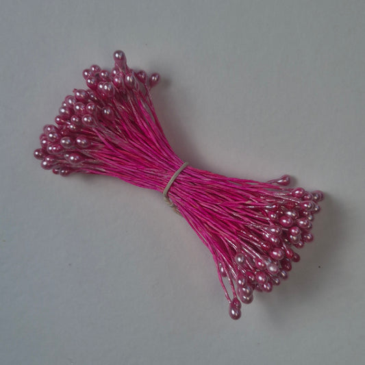 A bundle of size L Japanese miniature flower stamens, featuring bright pink pearlescent heads on vibrant raspberry cotton threads, arranged next to a transparent ruler