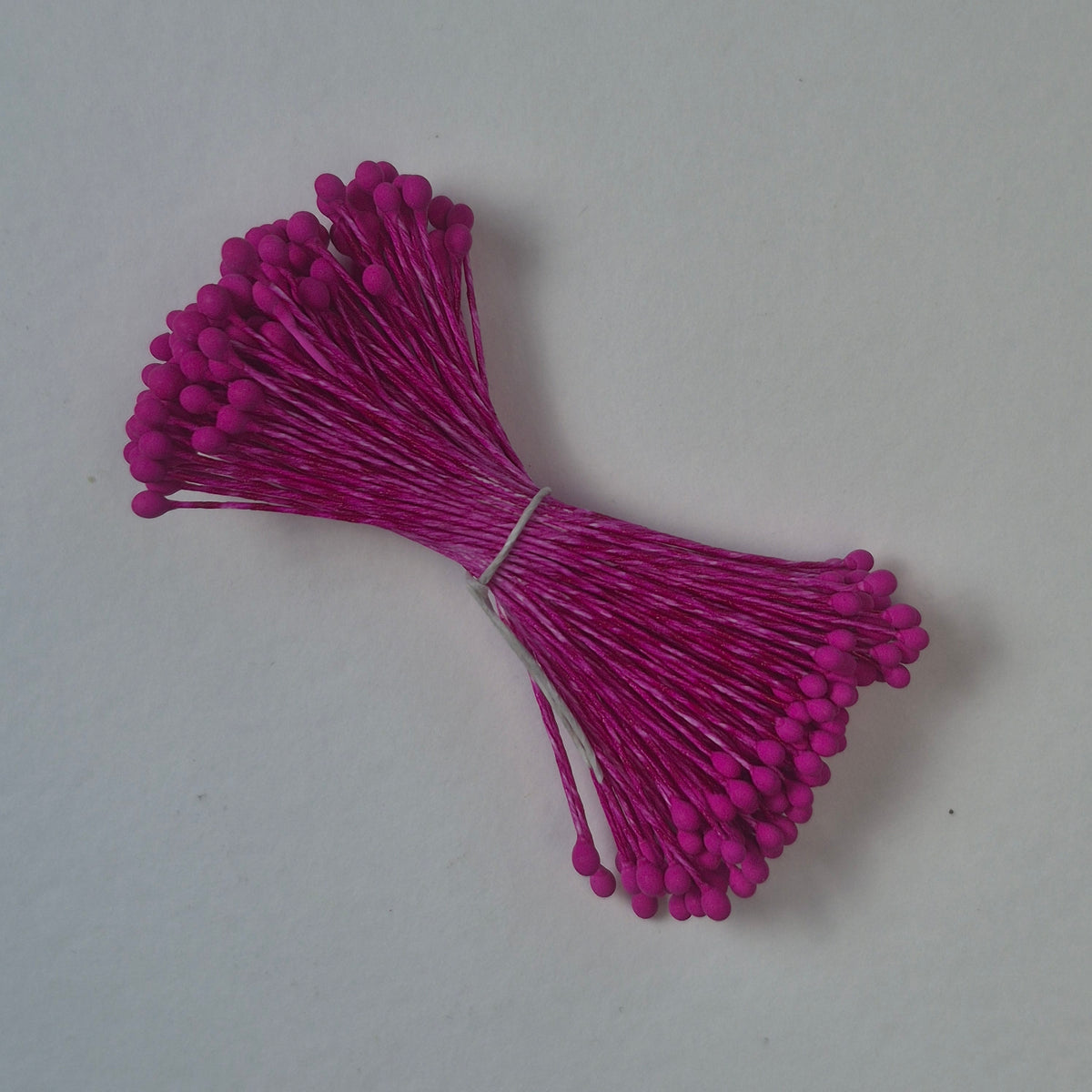 A bundle of size L Japanese miniature flower stamens, featuring vibrant fuchsia heads on matching fuchsia cotton threads, arranged next to a transparent ruler