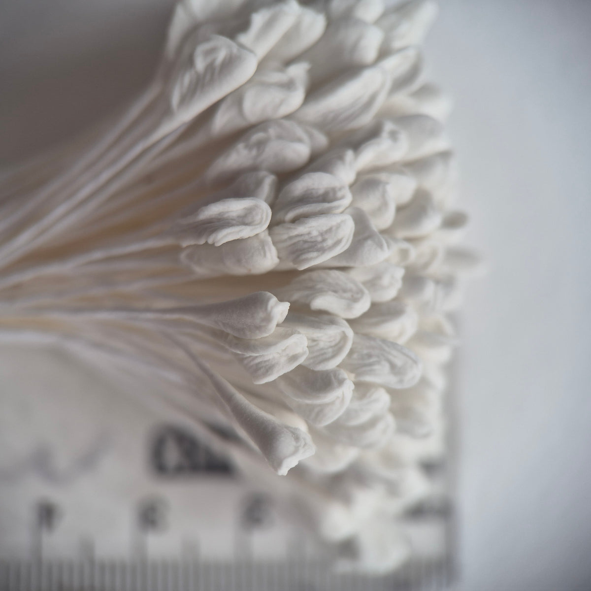 A bundle of 144 single-sided extra-large size XL white decorative Japanese flower stamens for lilies and tulips on matching white threads, featuring large handmade elongated heads measured against a ruler