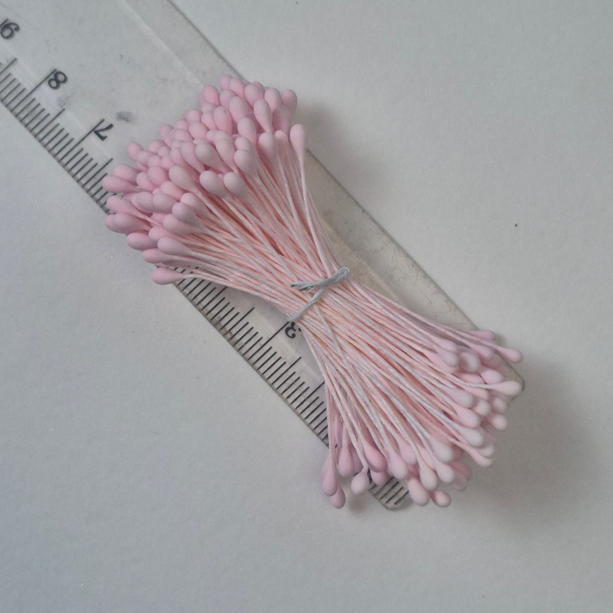 A bundle of size L Japanese flower stamens, featuring vibrant pink droplet-shaped heads on matching pink cotton threads.