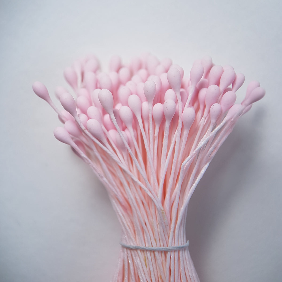 A bundle of size L Japanese flower stamens, featuring vibrant pink droplet-shaped heads on matching pink cotton threads.