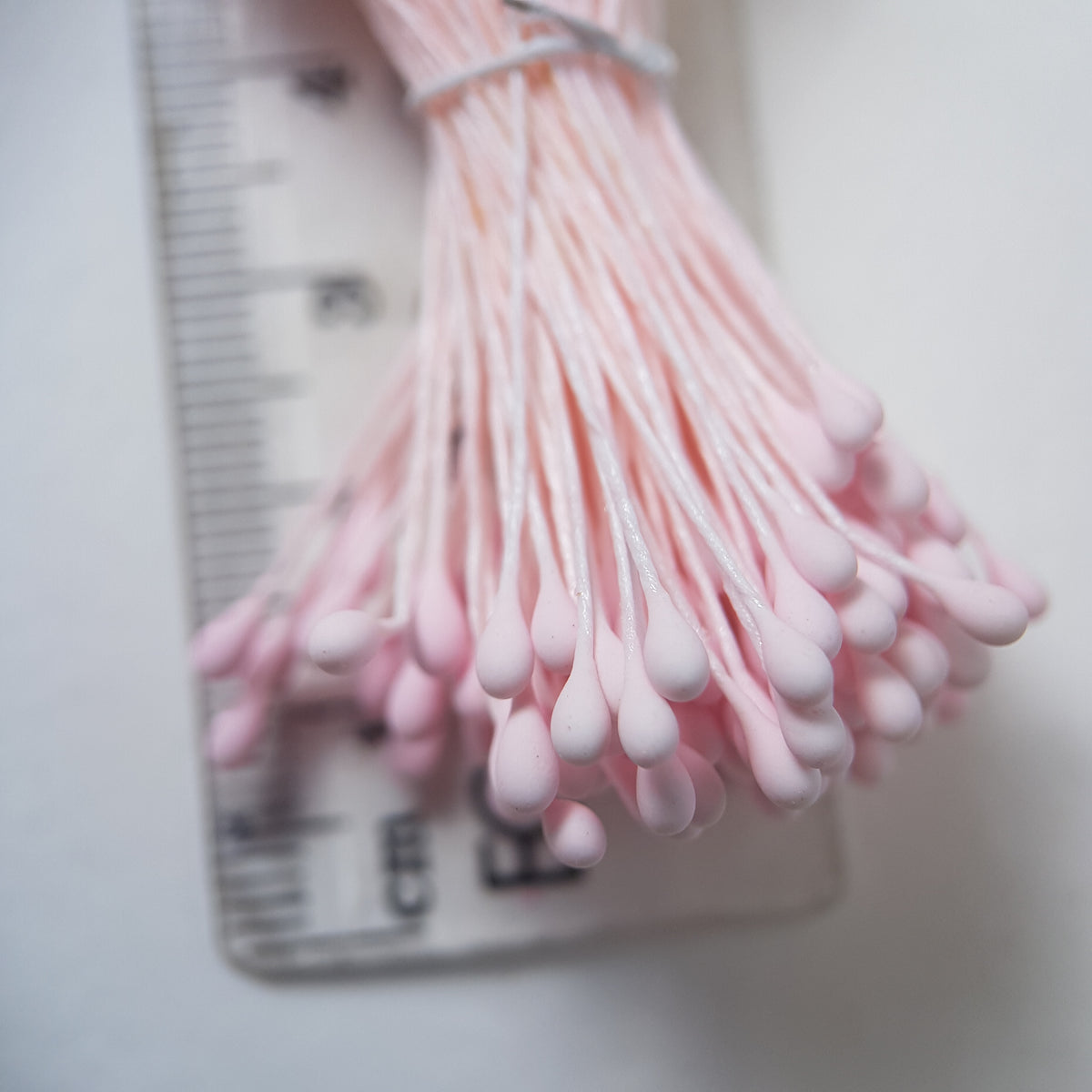 A bundle of size L Japanese flower stamens, featuring vibrant pink droplet-shaped heads on matching pink cotton threads.