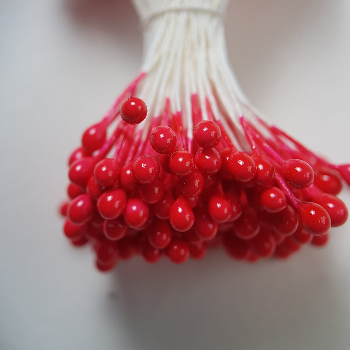 A bundle of size L Japanese flower stamens, featuring vibrant red round heads on white cotton threads.