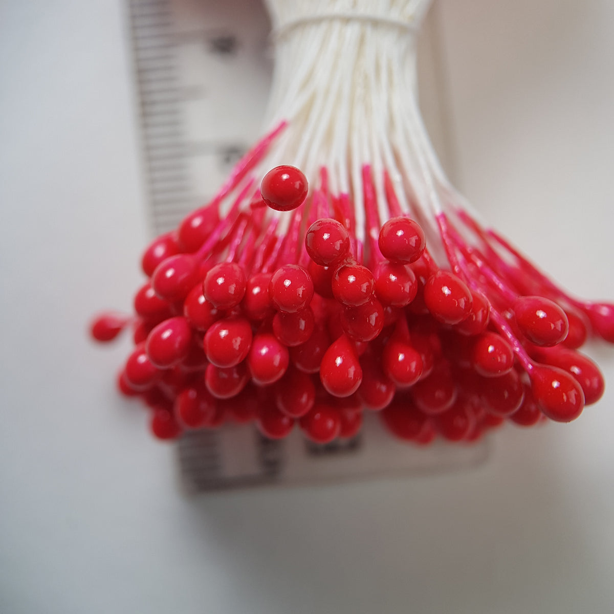 A bundle of size L Japanese flower stamens, featuring vibrant red round heads on white cotton threads.