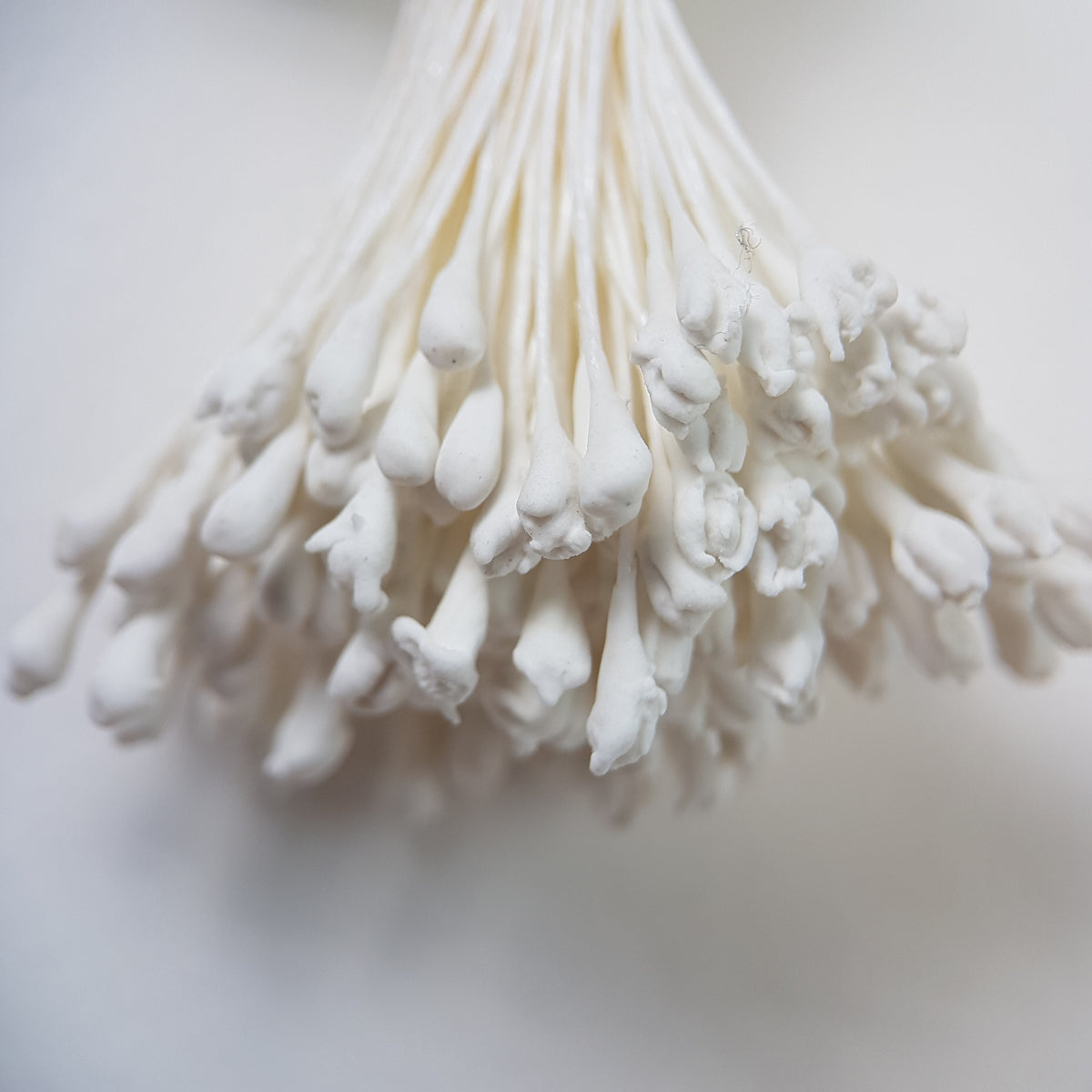 A bundle of extra-large size XL naturalistic Japanese flower stamens made of white rice flour and rayon threads, arranged next to a transparent ruler