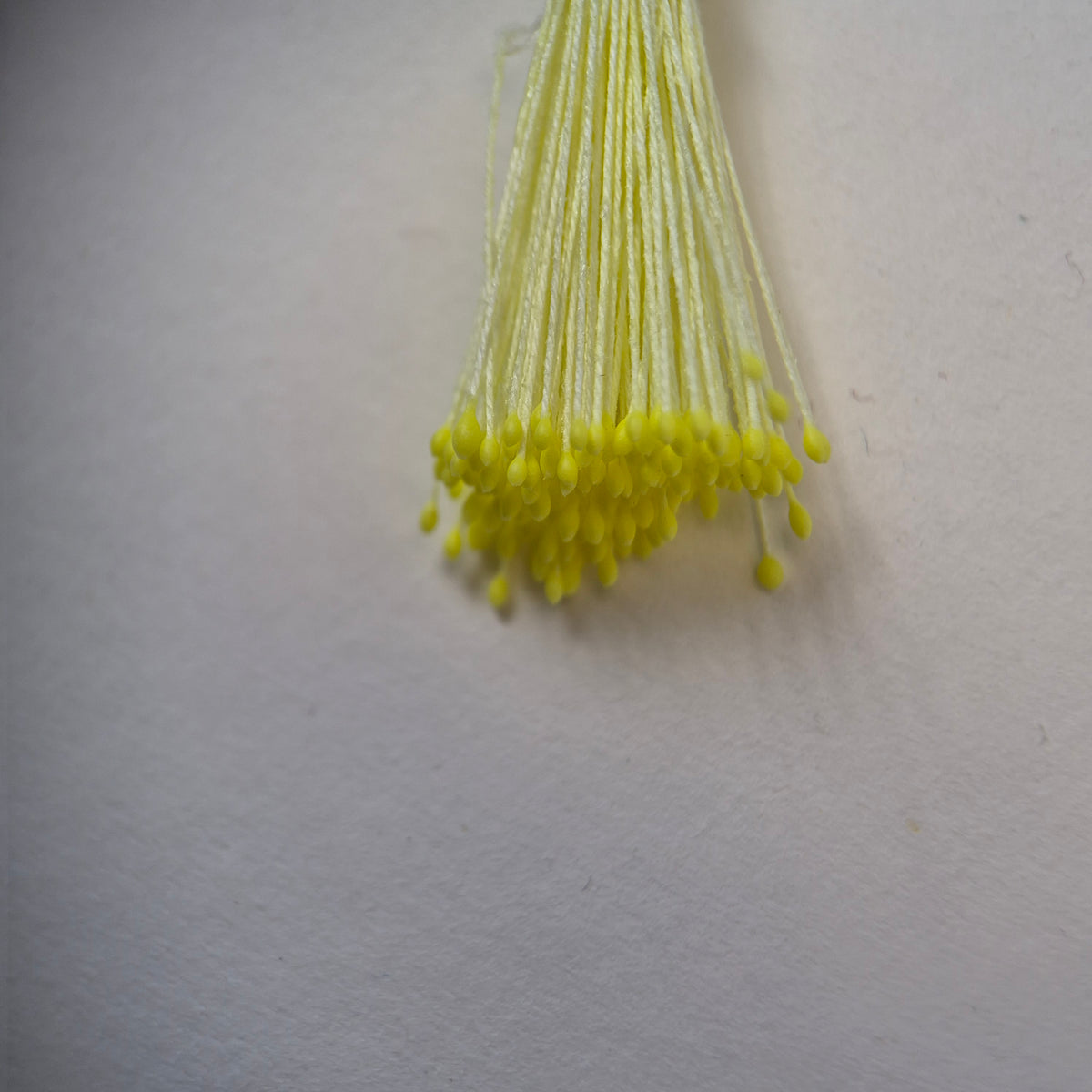 Small bundle of bright yellow round flower stamens on soft yellow cotton thread for silk floristry