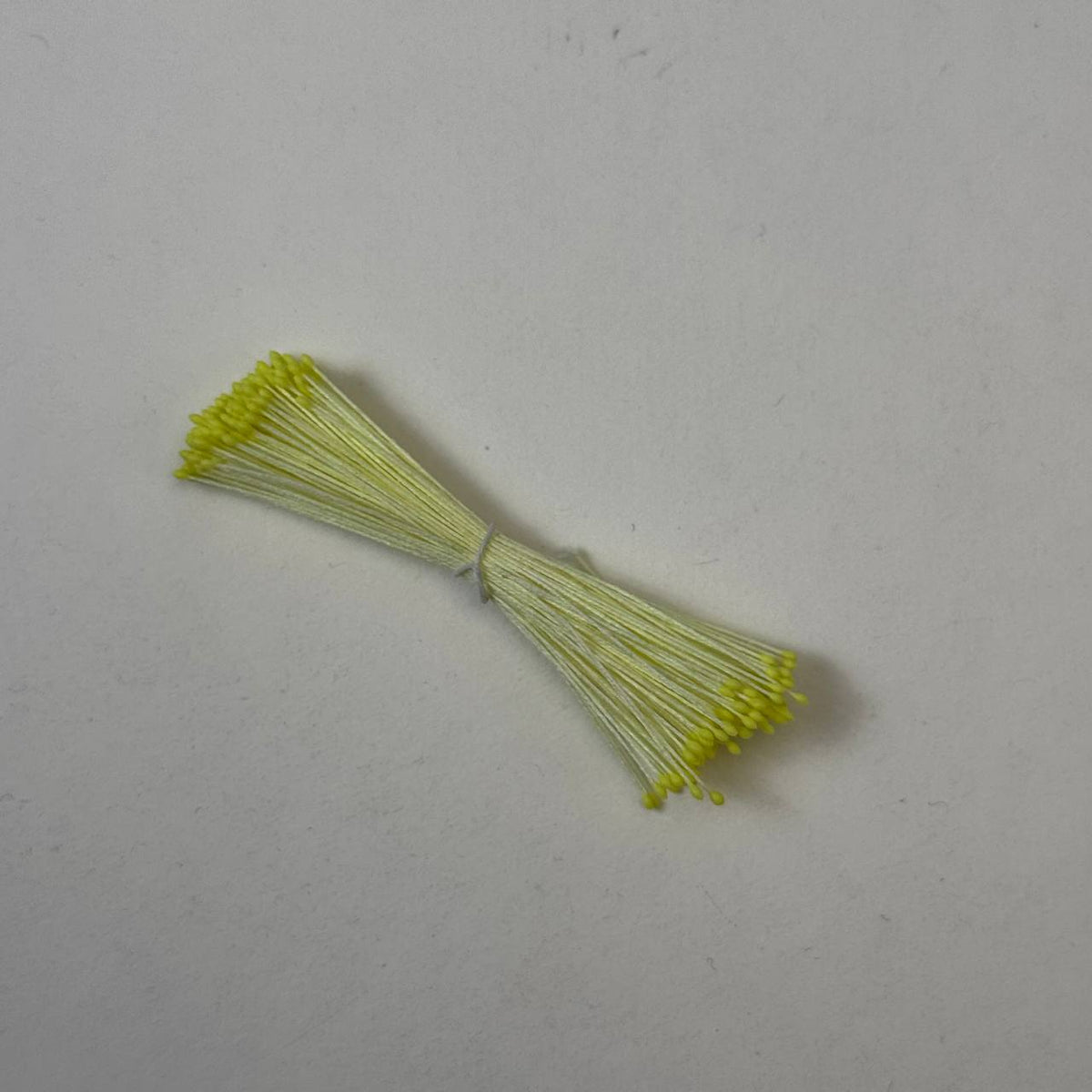 Small bundle of bright yellow round flower stamens on soft yellow cotton thread for silk floristry