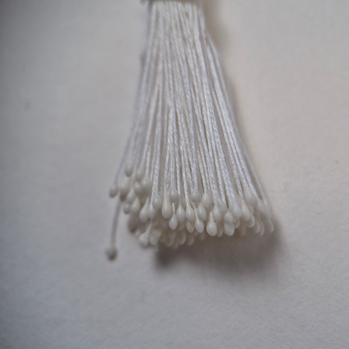 Small bundle of white round flower stamens on white cotton thread for silk floristry
