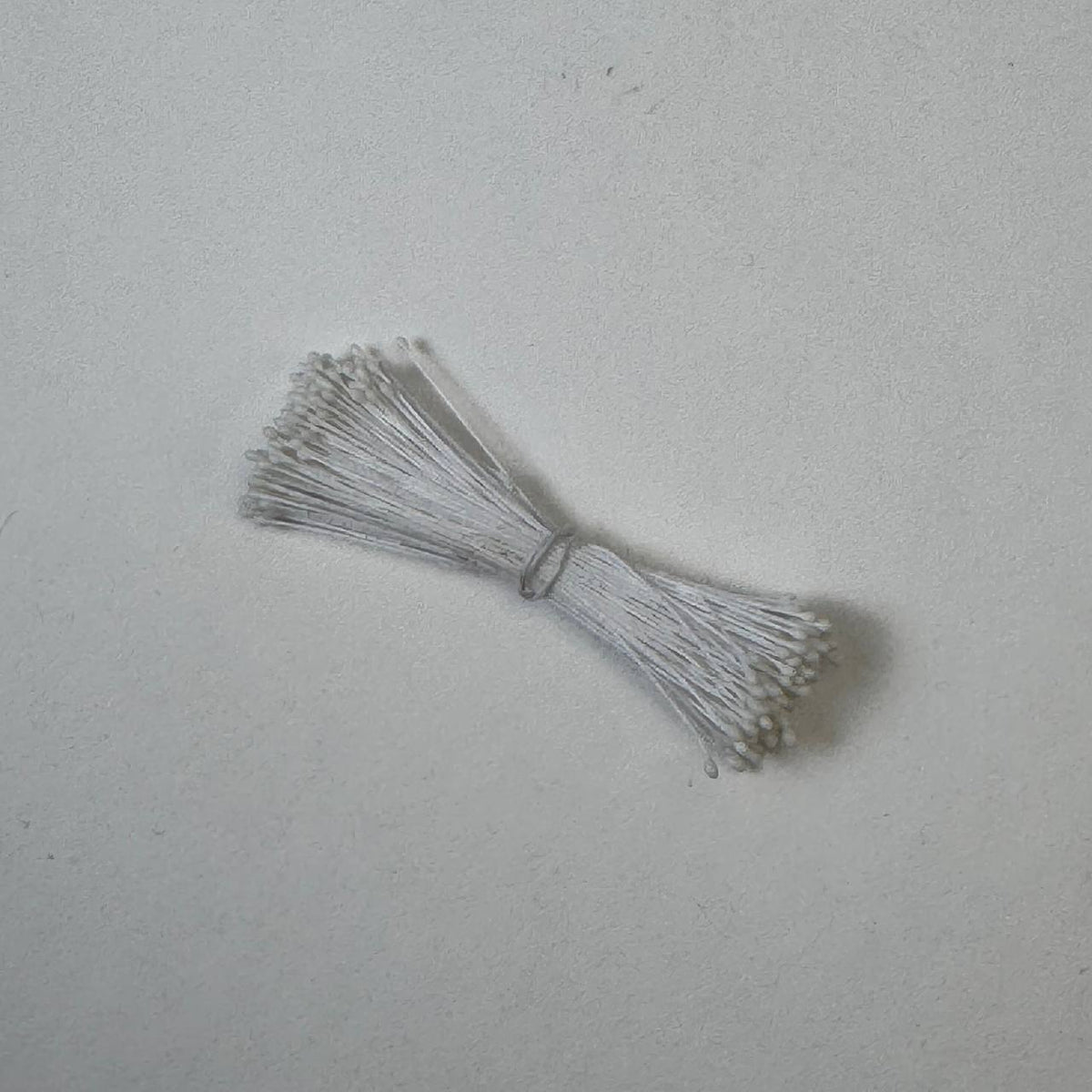 Small bundle of white round flower stamens on white cotton thread for silk floristry