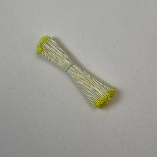 Small bundle of tiny yellow round flower stamens on cream cotton thread for silk floristry
