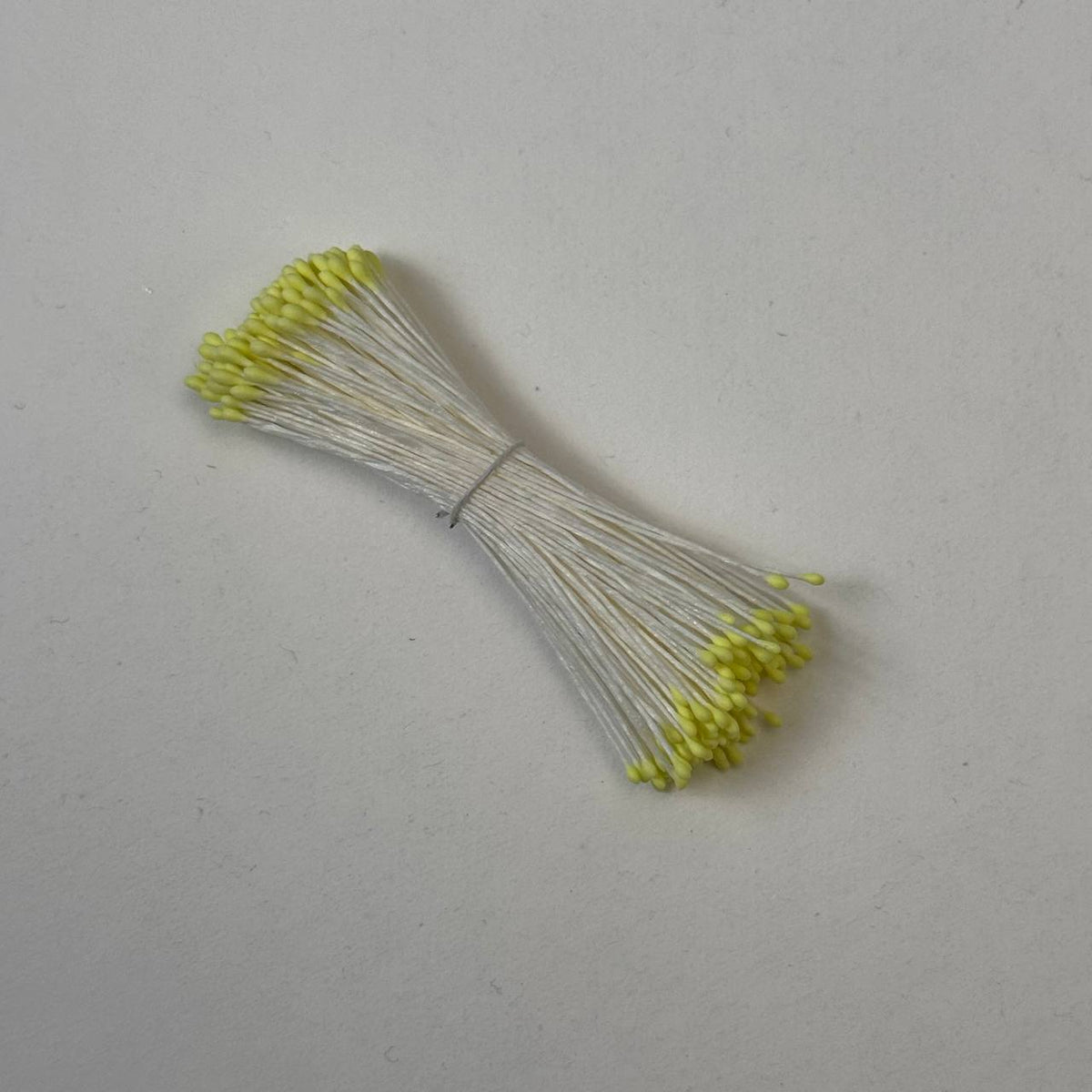 Small bundle of tiny yellow round flower stamens on cream cotton thread for silk floristry
