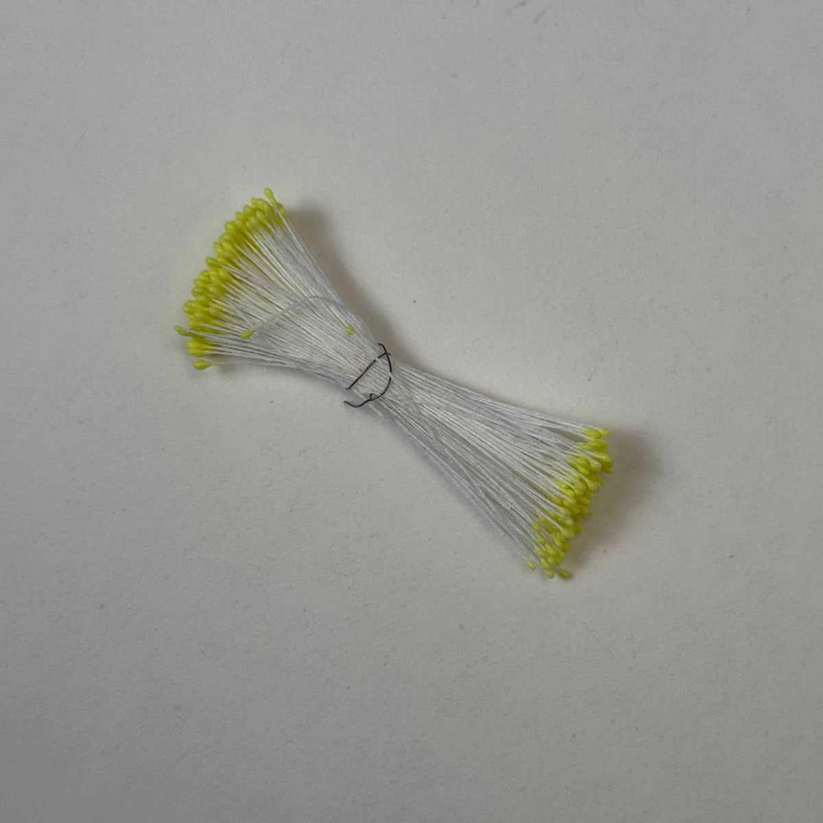 Small bundle of tiny yellow round flower stamens on snow white cotton thread for silk floristry